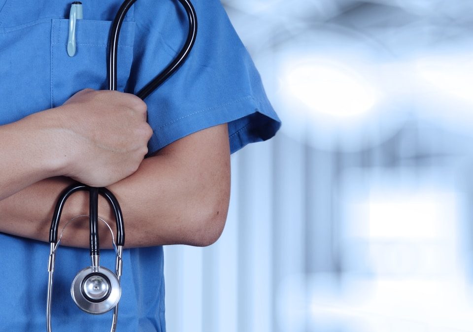 a person in scrubs with a stethoscope on their arm