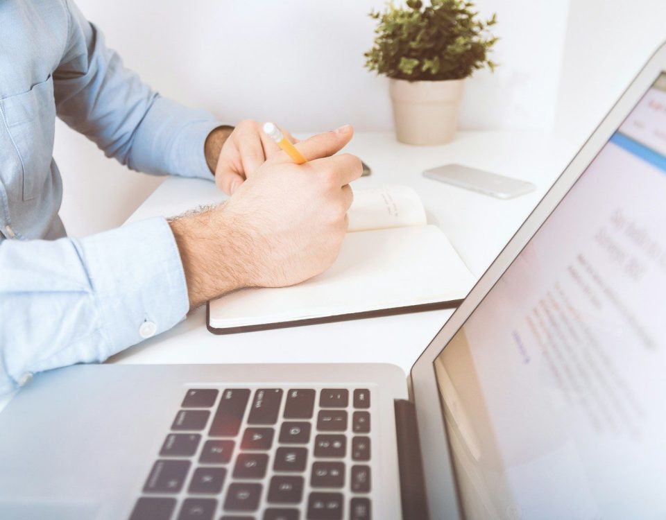 person writing on white notebook